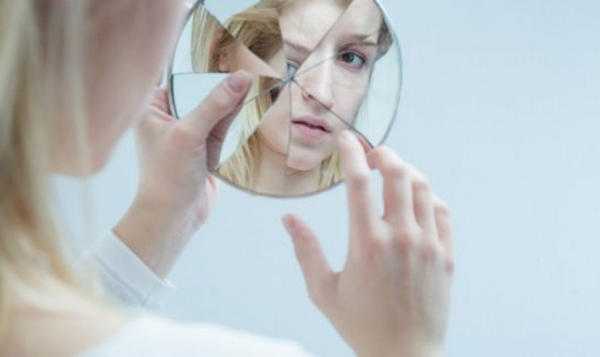 la fille regarde dans le miroir brisé 
